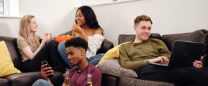 A group of young professional housemates sat on a settee in a fully furnished house share
